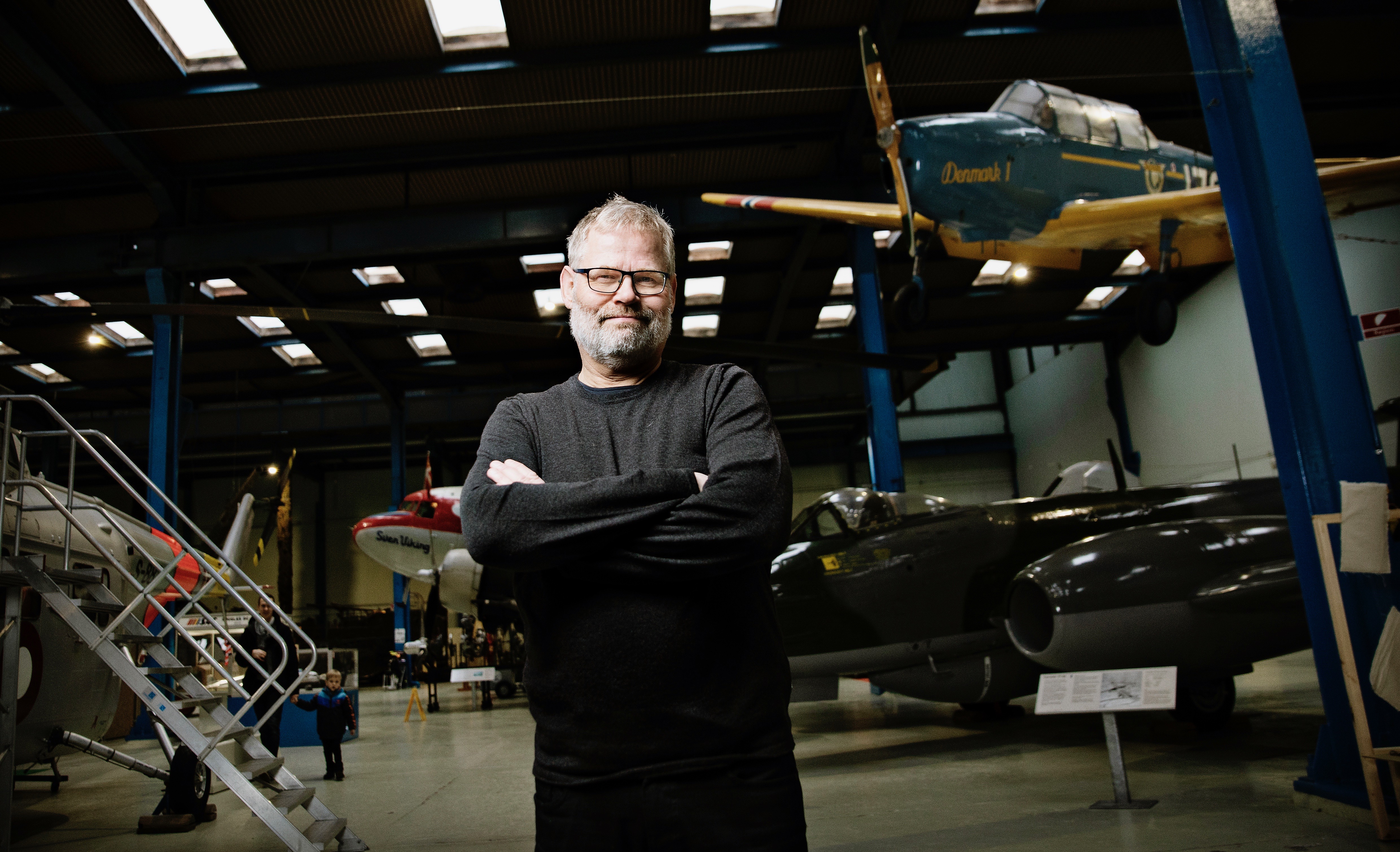 Torkild Adsersen, museuminspektør på Danmarks Tekniske Museum, fotograferet på museet omgivet af flyvemaskiner.